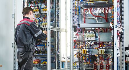 Electrician screwing equipment at electrical fusebox or switch box