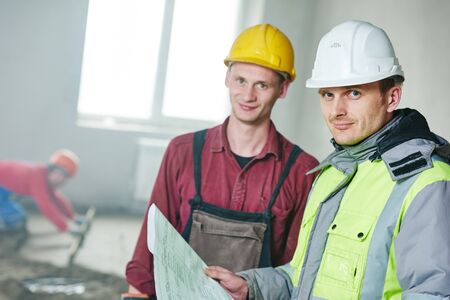 foreman builder and construction worker with blueprint in indoor apartment