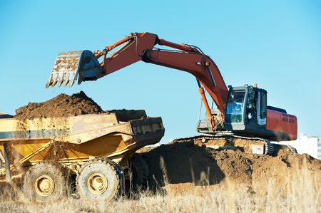 loader excavator machine loading dumper truck at sand quarry. Earthmoving workの写真素材