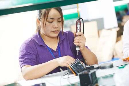 chinese female worker in assembling electronic device on factoryの写真素材