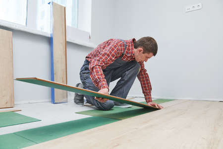 worker laying laminate floor covering at home renovationの写真素材