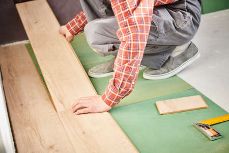 worker laying laminate floor covering at home renovationの写真素材