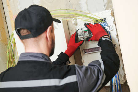 Electrician works with switchbox. installing circuit breaker