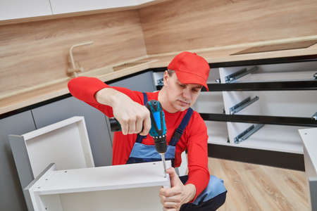 kitchen installation. Worker assembling furniture