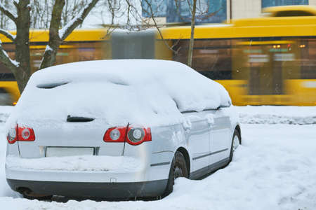 City winter snowfall. Car covered with snow on streetの写真素材