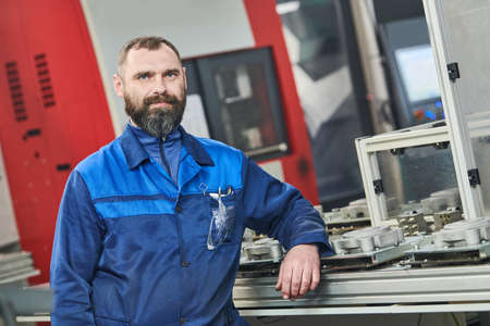 Industrial worker operating cnc machine at metal machining industry