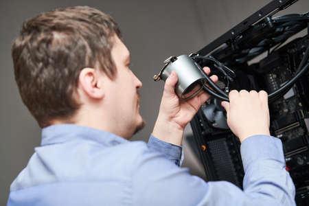 Computer assembling service. Serviceman installing liquid cooling system on processor