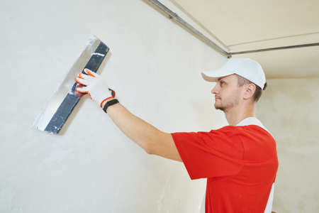 Plasterwork and wall painting preparation. craftsman applying plaster or fillingの写真素材