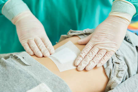 surgeon applies bandage on wound of childs abdomenの写真素材