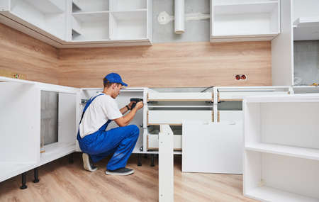 kitchen installation. Worker assembling furnitureの写真素材