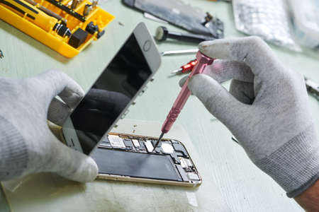 smart phone repair. repairman disassembling smartphone for maintenanceの写真素材