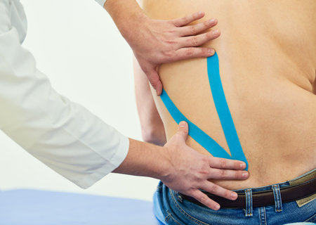 therapeutic strip tape applying on male back for pain reliefの写真素材