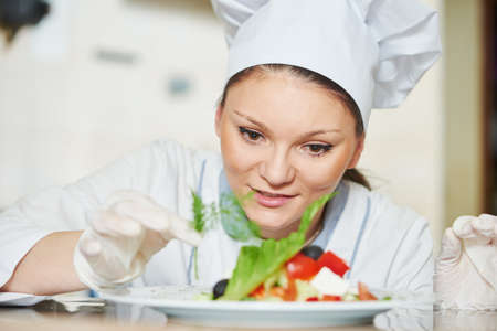 female cook chef decorating prepared salad foodの写真素材