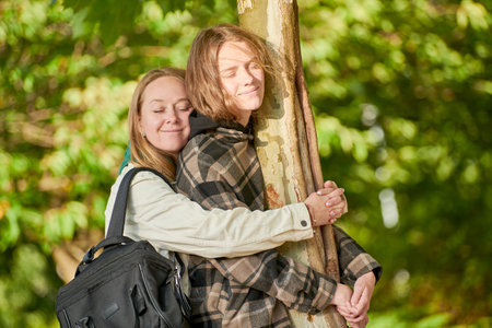 Family relationships. Teenager and mother relaxing together near treeの写真素材