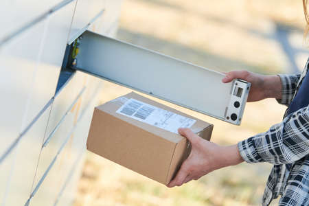 shipping and online buying concept. sending or receiving parcel at self service pickup point machineの写真素材