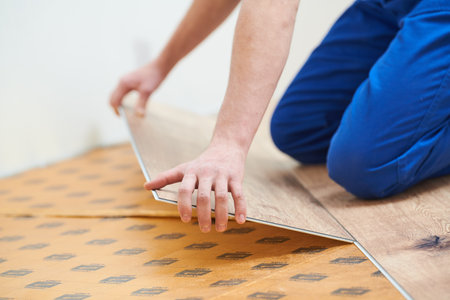 vinyl floor installation. Close-up hands of worker at home flooring renovation.の写真素材