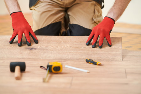 vinyl floor installation. Close-up hands of worker at home flooring renovation.の写真素材