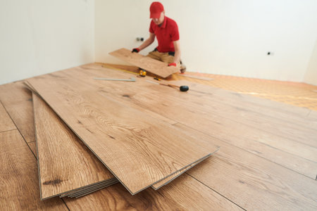 vinyl floor installation. Close-up hands of worker at home flooring renovation.の写真素材