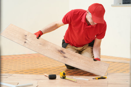 vinyl floor installation. Close-up hands of worker at home flooring renovation.の写真素材