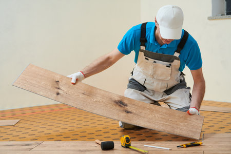 vinyl floor installation. Close-up hands of worker at home flooring renovation.の写真素材