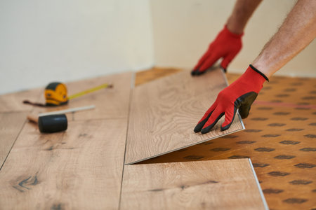 vinyl floor installation. Close-up hands of worker at home flooring renovation.の写真素材