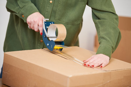 packing a parcel. sealing carton box with tape for shippingの写真素材