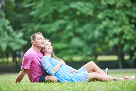 motherhood and pregnancy. family with pregnant woman outdoors in parkの写真素材