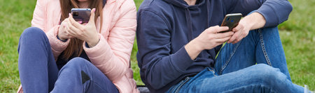 young woman and man sitting together and looking at smartphone separately. gadget addictionの写真素材