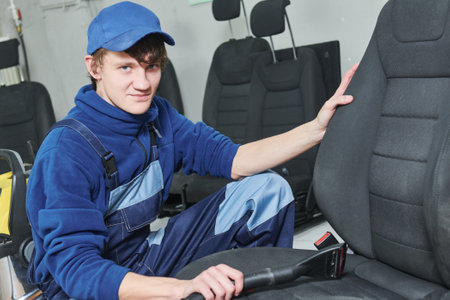 automobile detailing. Portrait of worker during car seat cleaning with vacuum cleanerの写真素材