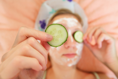 Young woman with cucumber slices on the faceの写真素材