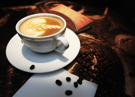 White cup of coffee with beans on the deskの写真素材