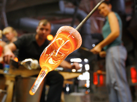 Glass furnace. Man holding a red-hot glass