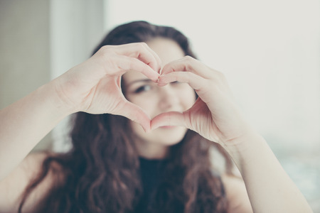 Beautiful young woman doing a heart shape with her hands.の写真素材