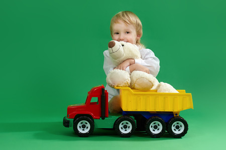 Boy sitting on the floor and playing with toys, green backgroundの写真素材