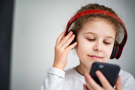 little girl in red headphones with a phoneの写真素材
