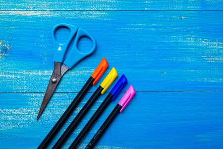 scissors pens and beads on a blue tableの写真素材