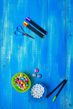 scissors pens and beads on a blue tableの写真素材