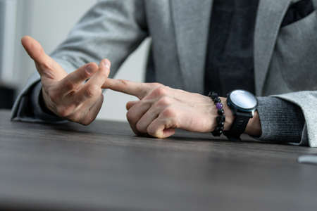 partial view of businessman with hands in lock sitting at table, business concept, wristwatchの写真素材