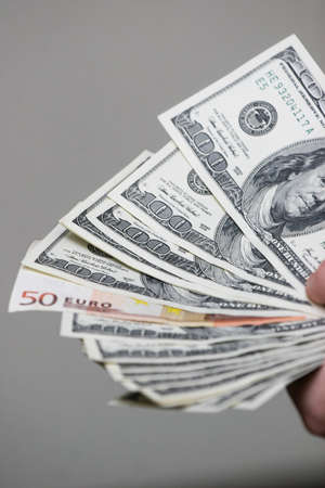 Minsk. Belarus - 17.04.2009: One hundred dollar bills and banknotes of 50 euros in a hand on a gray background.のeditorial素材