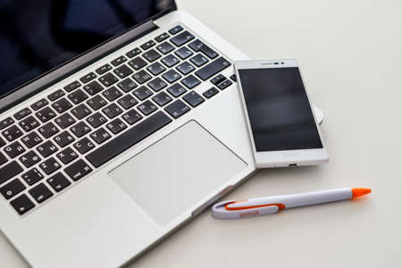Laptop, telephone, pen on the gray table. Office work. High quality photoの写真素材