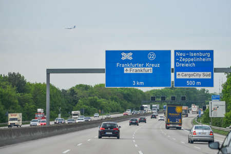 GERMANY - AUGUST 2015: Traffic on the Autobahn, direction signs, distances to cities. Cars on the track. An airplane is flying in a background. High quality photoのeditorial素材