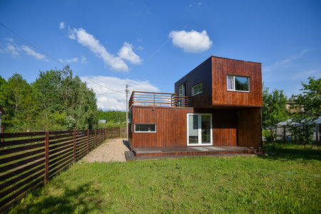 MINSK. BELARUS - MAY 2016: View of the brown modular house against the backdrop of greenery and blue sky in the clouds. High quality photoのeditorial素材