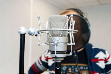 Studio microphone for professional recording. In the background, the man recording a voice. The...