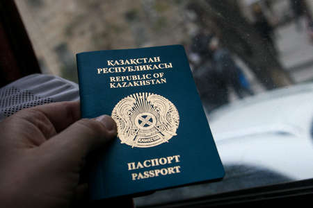 Azerbaijan, Baku - Nowember 2009: The passport of the Republic of Kazakhstan is held by a man. National emblem of the Republic of Kazakhstan.のeditorial素材
