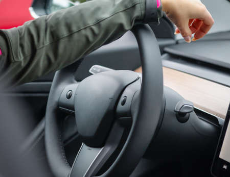 Womans hand on the steering wheel of an electric car. Electric car dashboard.