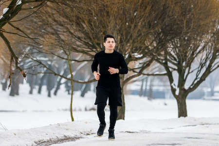 The young man goes jogging in winter while doing sports.の写真素材