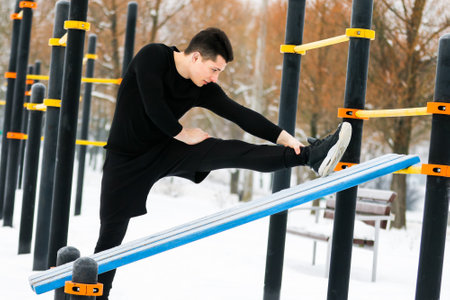 A man does push-ups in winter during morning sports with the help of the yellow exercise machine.