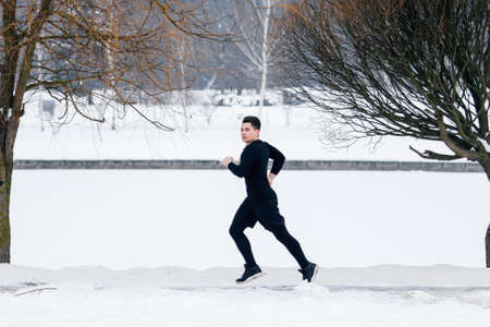 The young man goes jogging in winter while doing sports.の写真素材