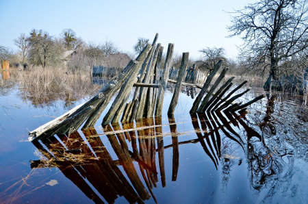 Belarus. Petrikov - April 2013: Flooding in a village. Flooded fence in spring, flood.のeditorial素材
