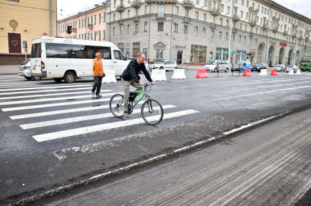 MINSK. BALARUS: 15.05.2013 - A pedestrian and a cyclist at a pedestrian crossing near a traffic jam due to road repairs.. Repair of the roadbed in the city.のeditorial素材